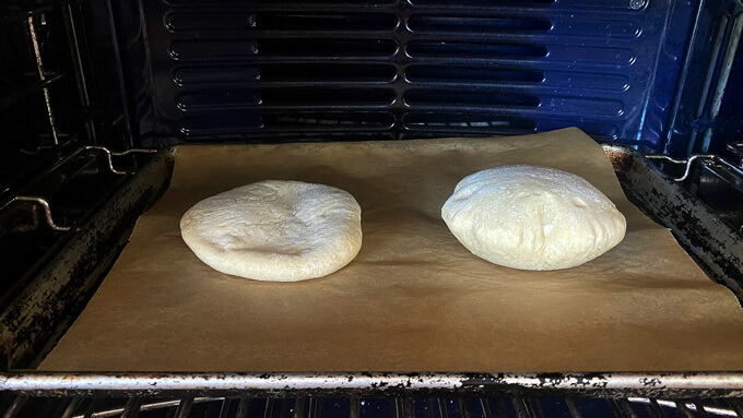 Two pita cooking on a non-preheated sheet pan. 