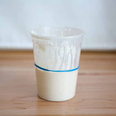 A quart container holding a just fed sourdough starter.